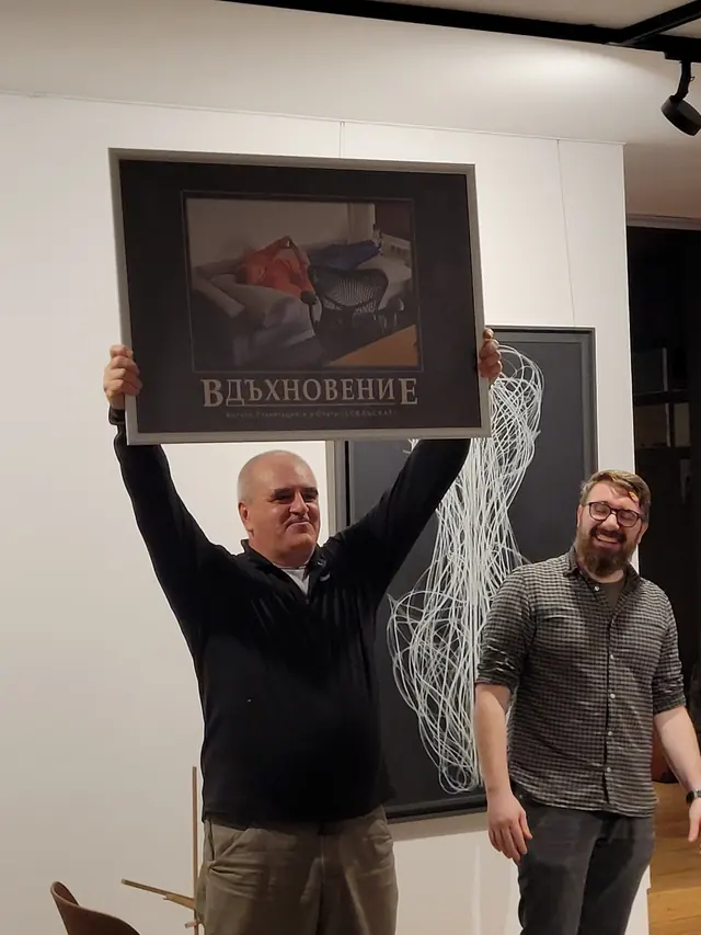 Two colleagues holding up a framed joke poster titled “Inspiration”